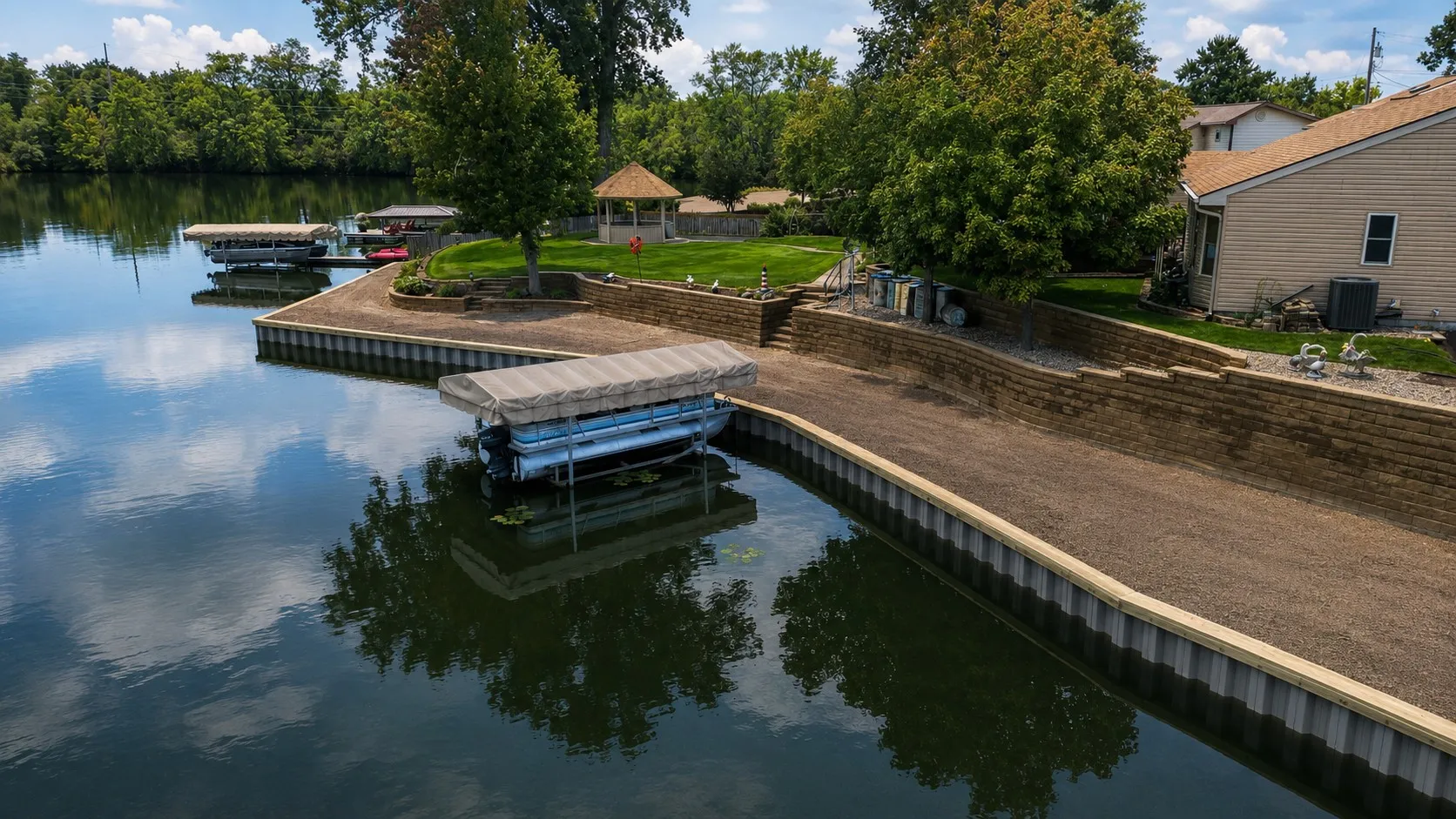 Aerial view of an Outback Construction project — a curving segmental retaining wall, boat dock and lift along a Southeast Nebraska lakefront